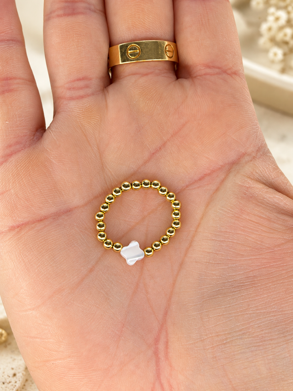 Gold-tone bead ring with a white clover accent