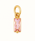 Single pink baguette crystal charm with gold-tone setting on off-white