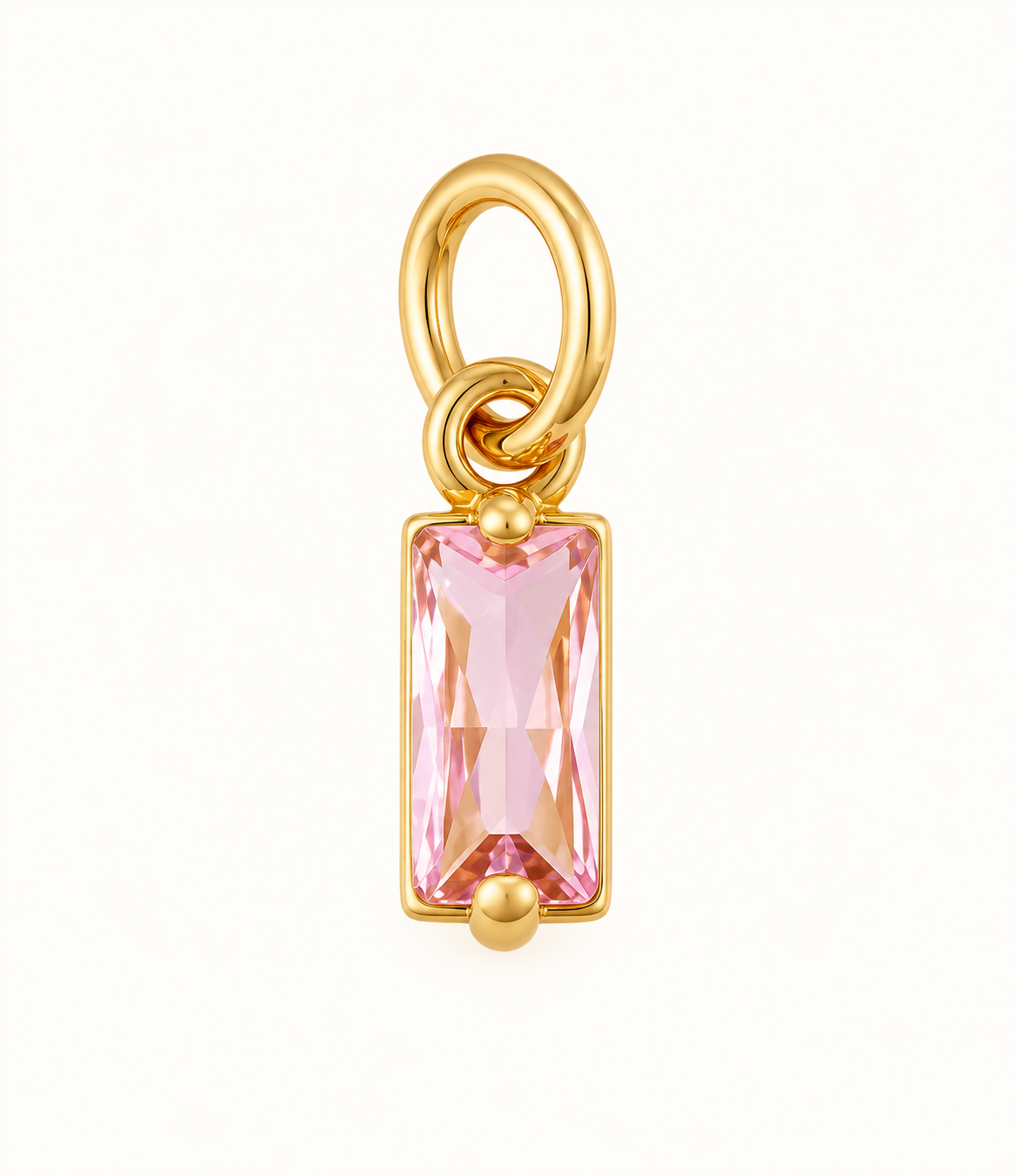 Single pink baguette crystal charm with gold-tone setting on off-white