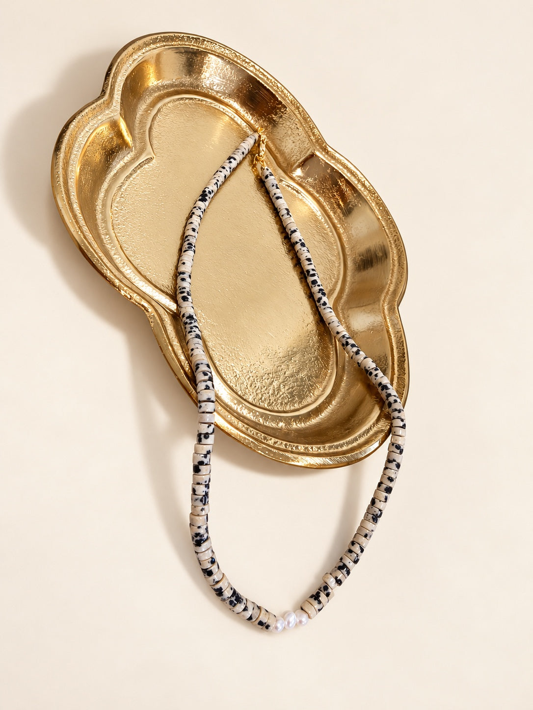 Dalmatian pearl necklace styled on a gold tray