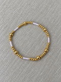 Lilac and gold beaded bracelet on neutral woven fabric