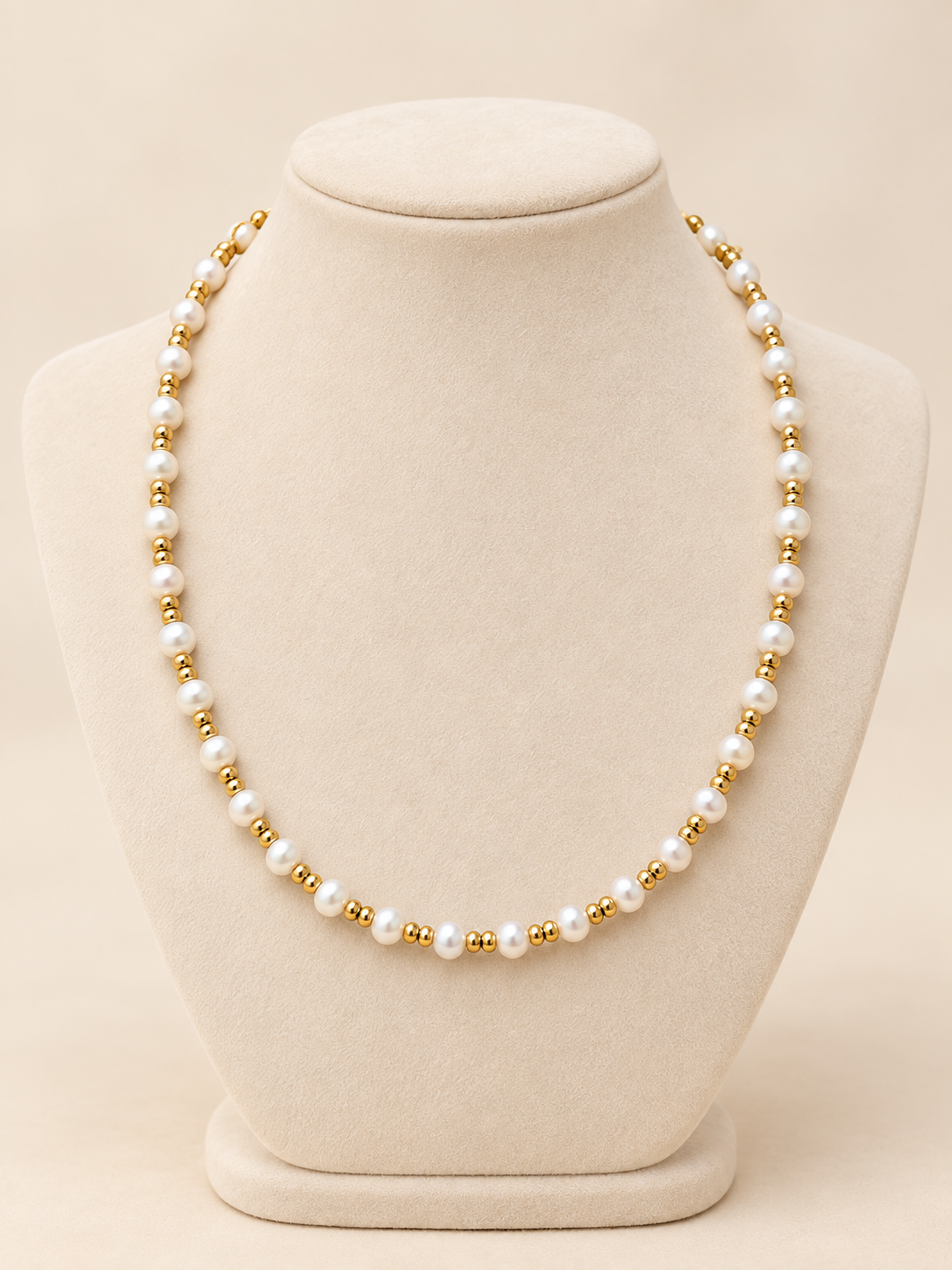 Pearl and gold beaded necklace displayed on an ivory velvet necklace holder