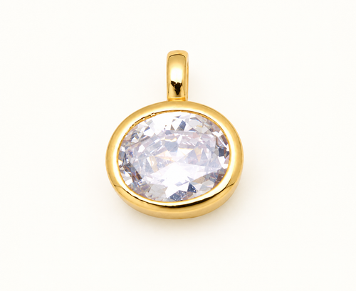 Single round clear crystal charm in a gold-tone bezel on off-white