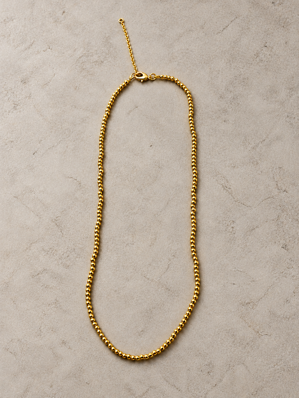 Simple gold beaded necklace laid flat