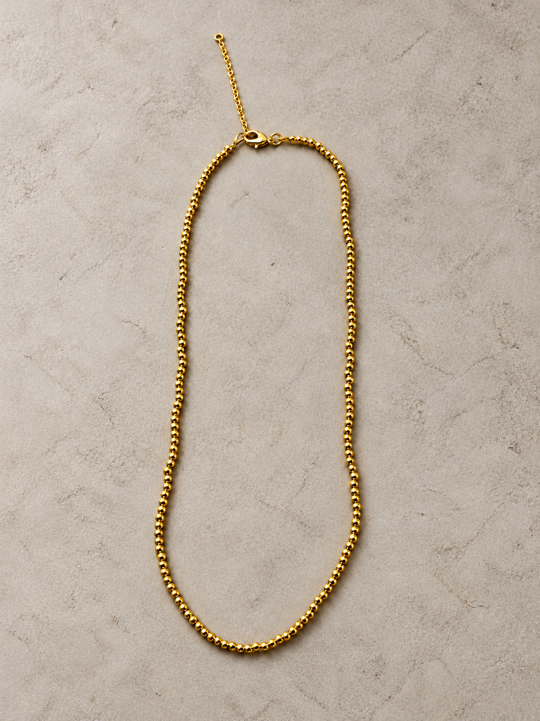 Simple gold beaded necklace laid flat