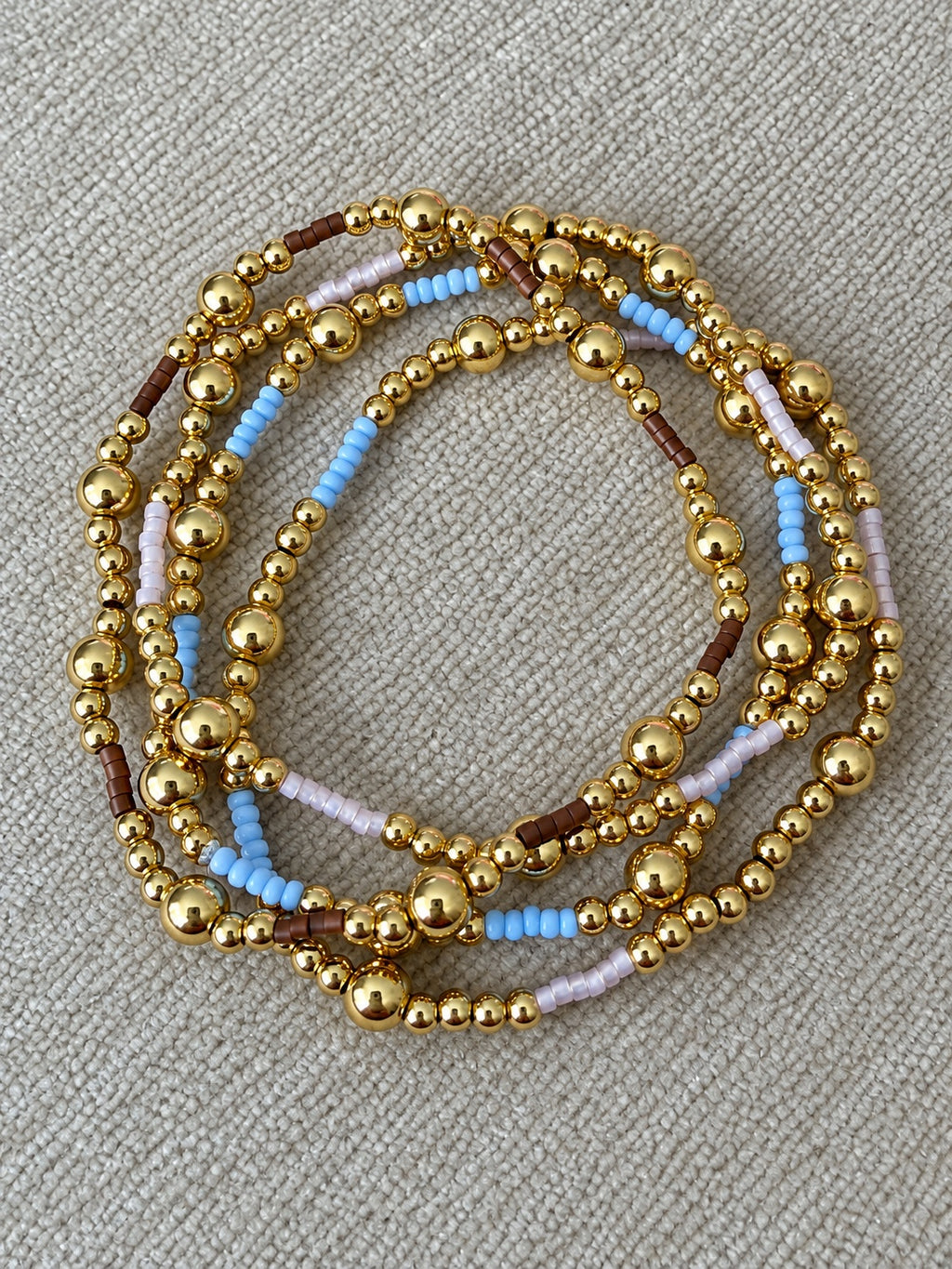 Sky, lilac, and mocha gold bead bracelets displayed together
