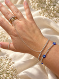Small blue evil eye beads on a silver-tone bead bracelet styled with separate hand chain and rings