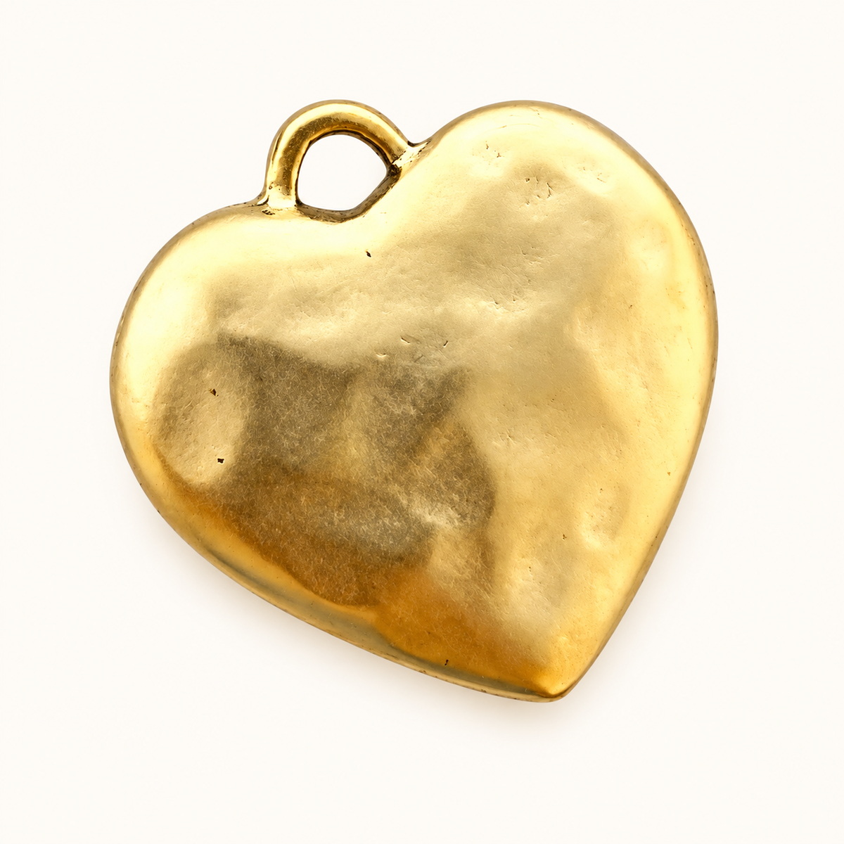 Single textured gold-tone heart charm on off-white