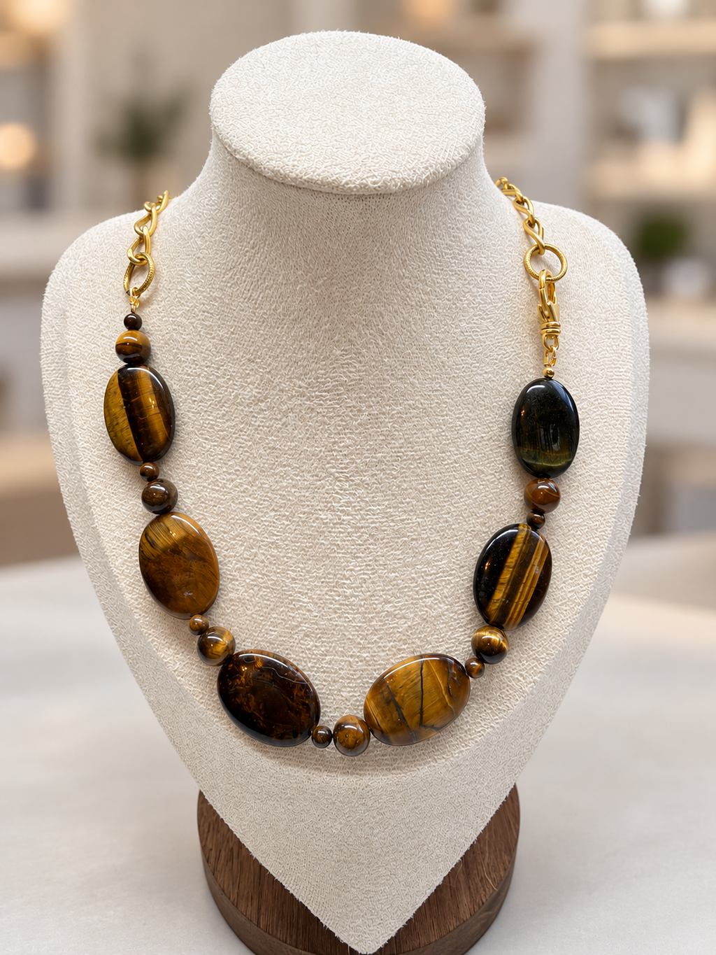 Tiger eye stone necklace with gold chain on a display bust