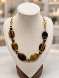 Tiger eye stone necklace with gold chain on a display bust